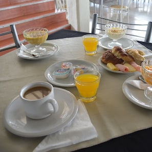 Una mesa de desayuno con platos de comida, vasos de jugo de naranja y una taza de café.