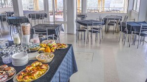 Un buffet proposant une variété de plats, avec des tables disposées dans une pièce spacieuse dotée de grandes fenêtres.