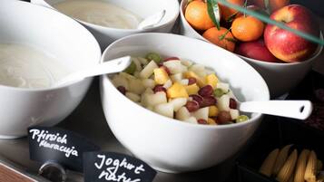 Bowls of yogurt, fruit salad, and oranges on a tray.
