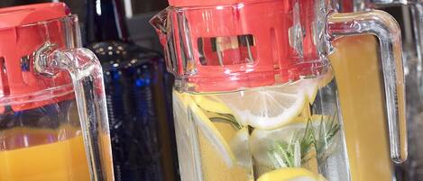 Una encimera de cocina con tres jarrones de vidrio que contienen bebidas, uno con tapa roja y los otros con tapas transparentes.