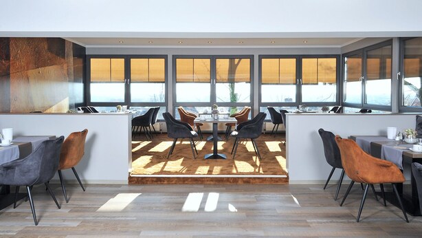 Un comedor moderno con una mesa central, rodeado de sillas, ventanas amplias y vistas al exterior.
