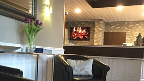 Una sala de estar moderna con un sofá de cuero negro, una alfombra blanca y un florero con flores moradas.