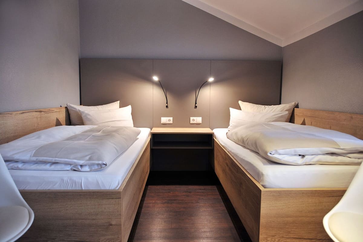 Habitació d'hotel moderna amb dos llits individuals, ambres de fusta i taules de nit.