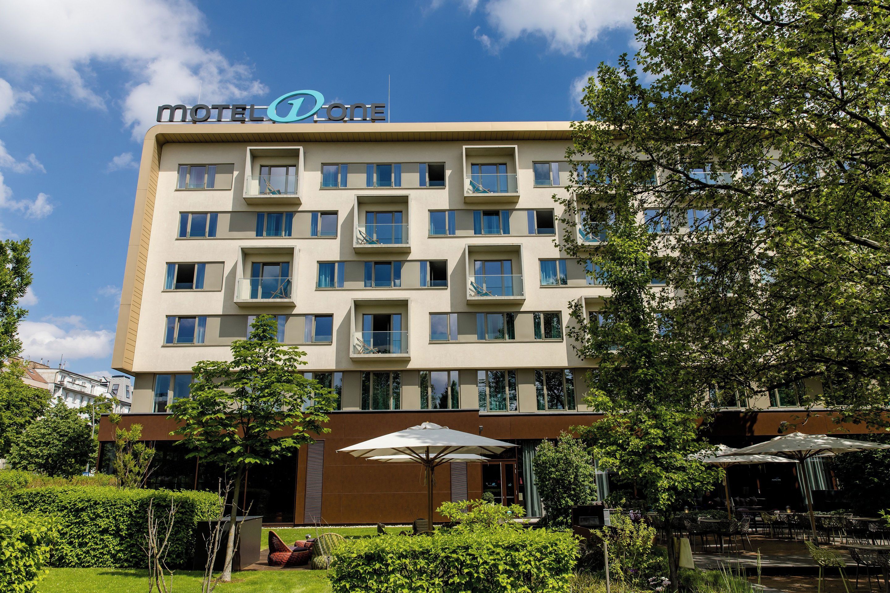 A multi-story motel with a modern design, featuring balconies and a central entrance.