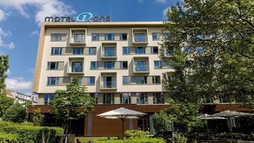 A multi-story motel with a modern design, featuring balconies and a central entrance.