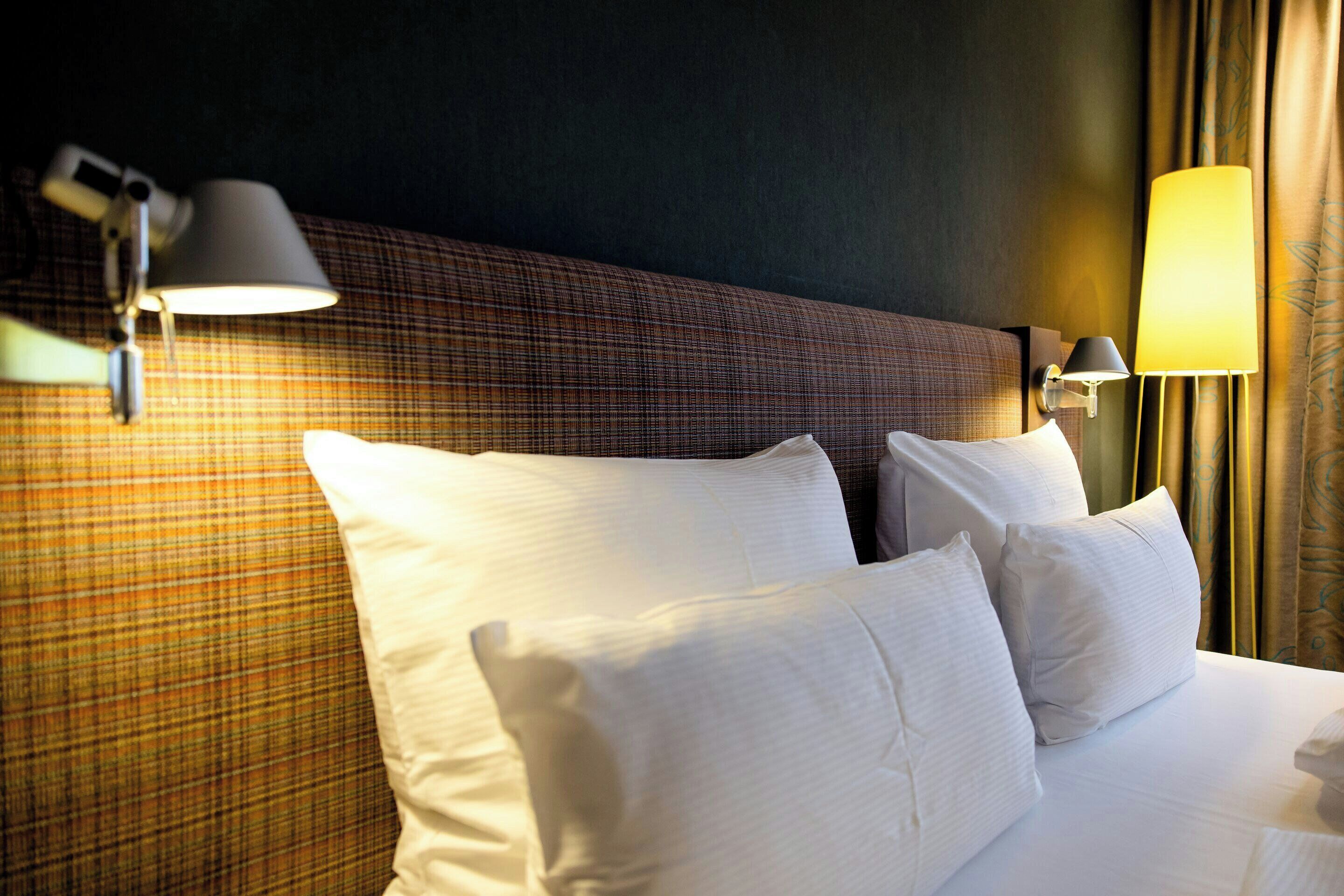Ein Hotelzimmer mit einem Bett, zwei Wandlampen und einem Kopfteil mit Karomuster.