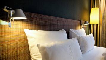 Ein Hotelzimmer mit einem Bett, zwei Wandlampen und einem Kopfteil mit Karomuster.