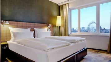 Ein Hotelzimmer mit einem großen Bett, zwei Nachttischen, einer Lampe und Blick auf ein Riesenrad.