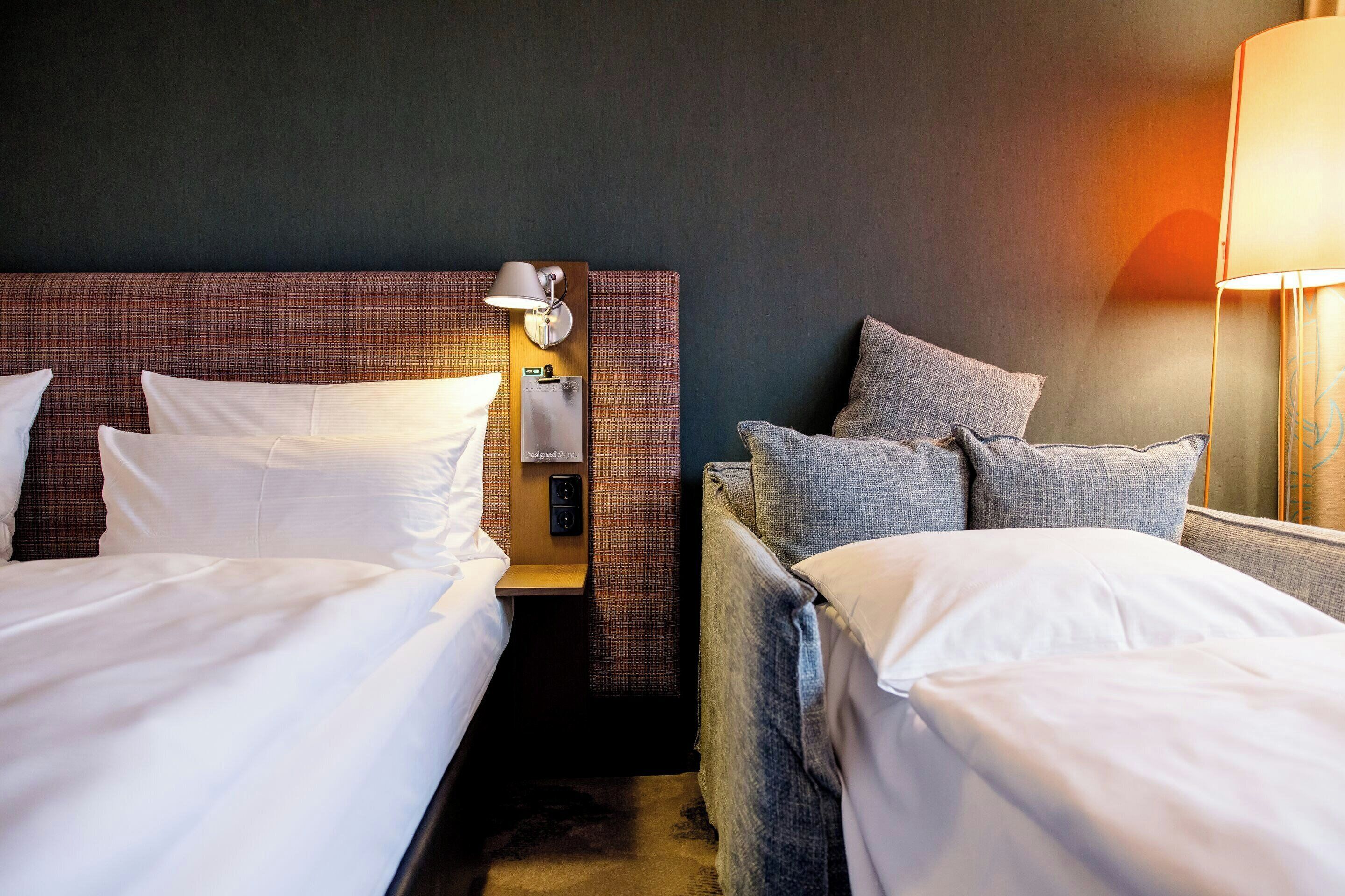 Une chambre d’hôtel avec deux lits, une tête de lit, des lampes de chevet et une table de chevet.