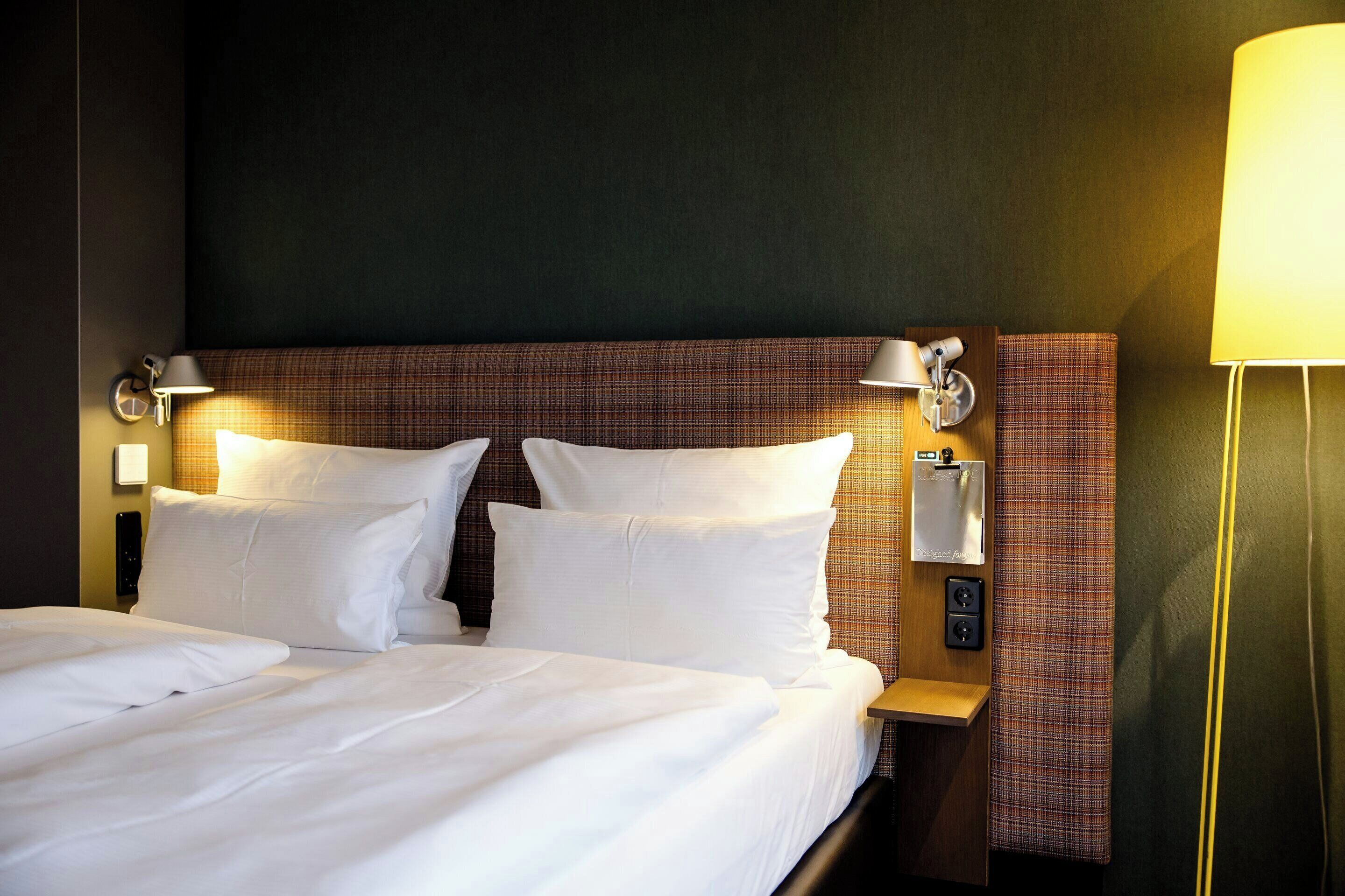 Ein Hotelzimmer mit einem großen Bett, zwei Nachttischen, einem Kopfteil und einer Wandlampe.