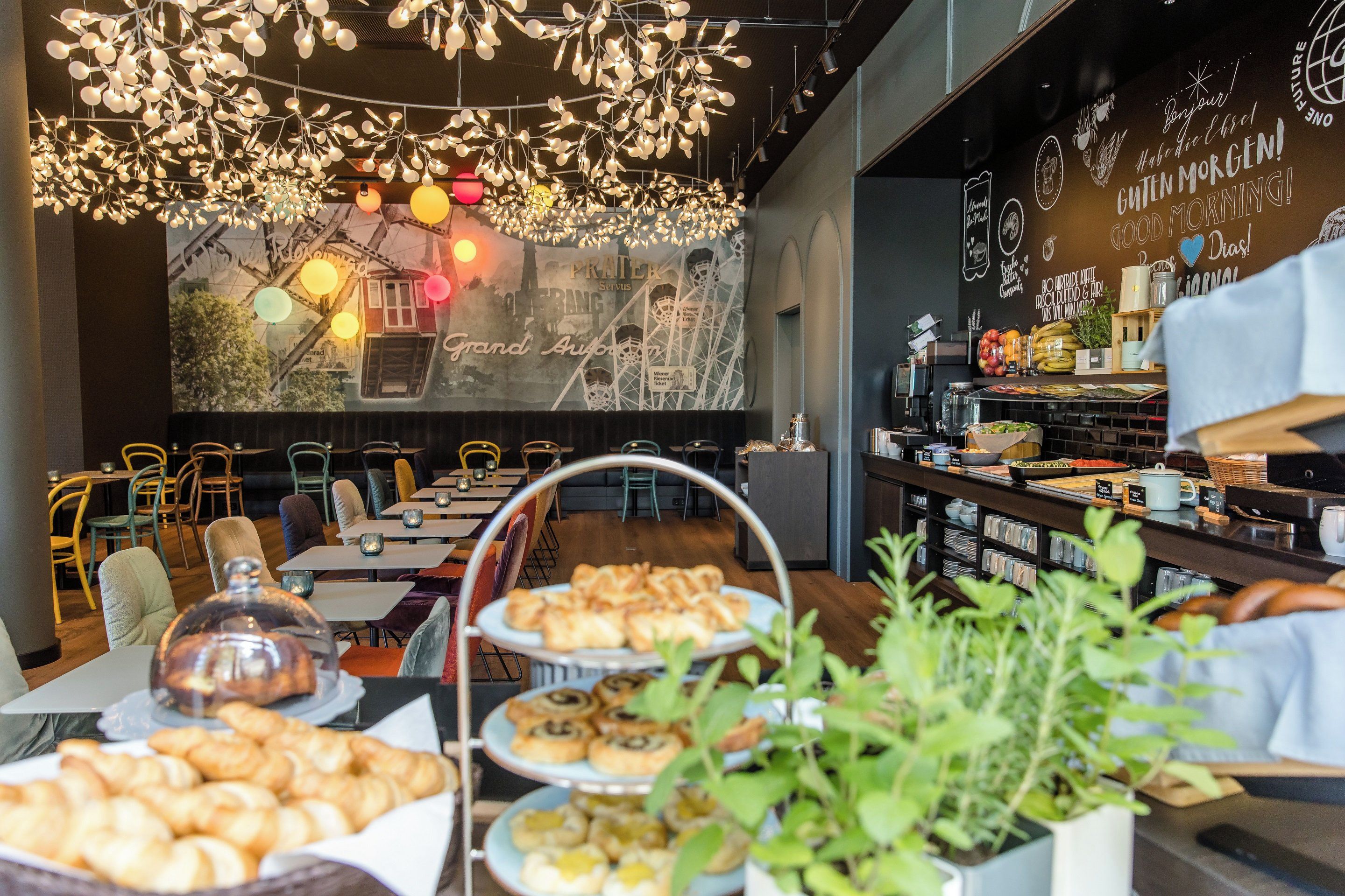 A café with a variety of pastries on display, a chalkboard menu, and a cozy seating area with tables and chairs.