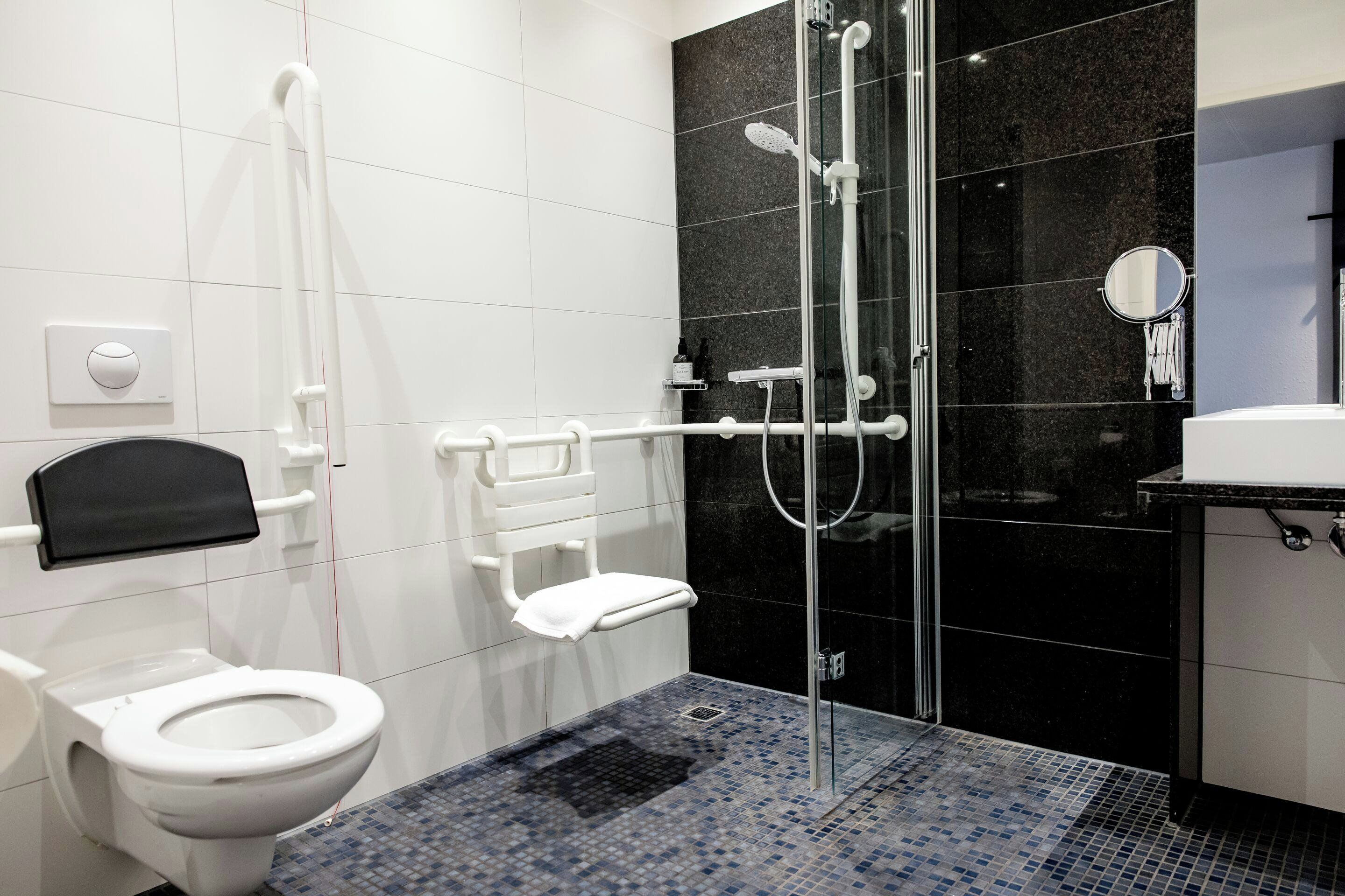 Une salle de bain moderne comprenant des toilettes, une douche avec une porte en verre, un lavabo et un miroir.