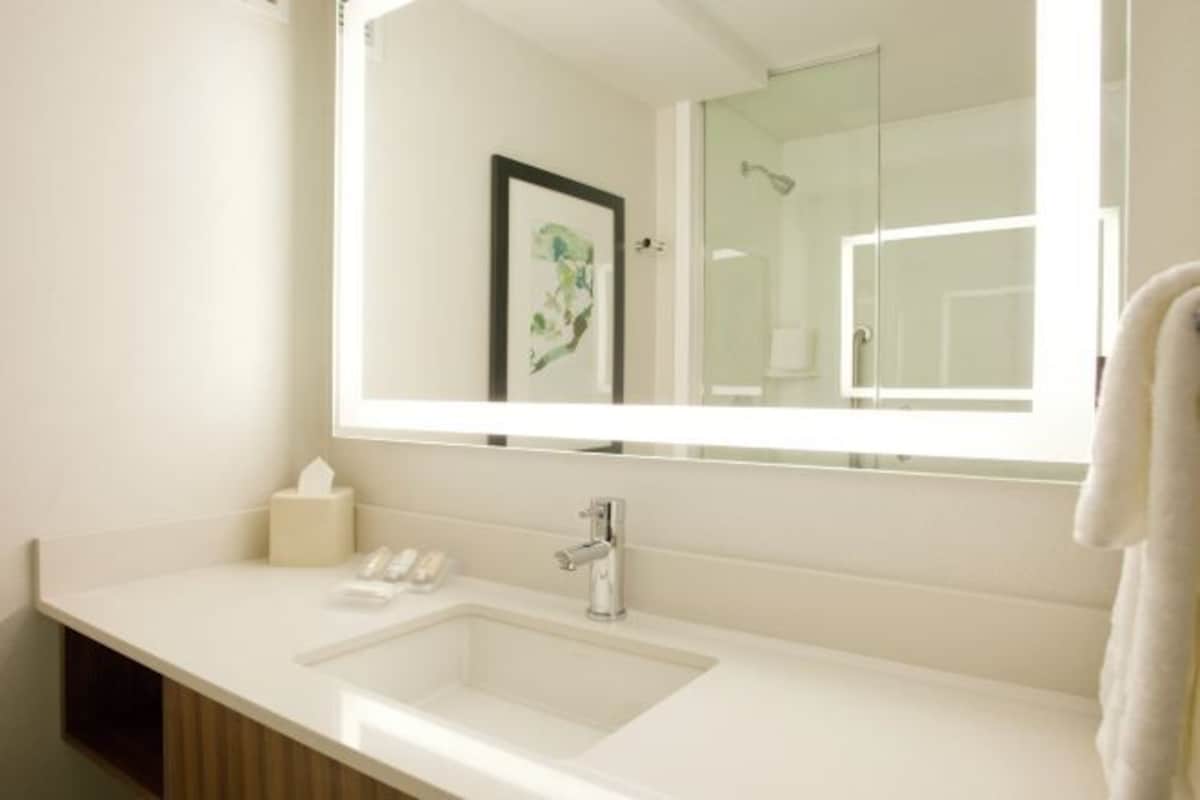 Un baño moderno con un espejo grande, un lavabo y un perchero para toallas.