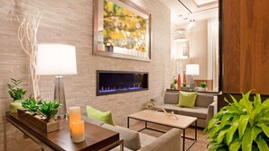 A modern living room with a fireplace, comfortable seating, and decorative plants. - Hilton Garden Inn New York/Central Park South-Midtown West (New York)
