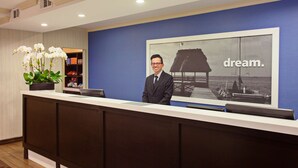 A reception desk with a large framed picture of a sailboat and the word "dream." in the background. - Hampton Inn Los Angeles Int'l Airport/Hawthorne (Hawthorne)