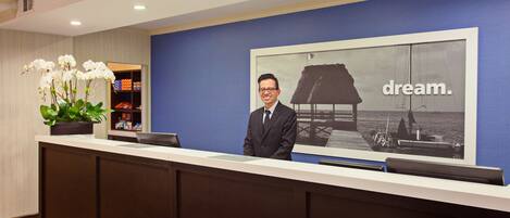 A reception desk with a large framed picture of a sailboat and the word "dream." in the background.