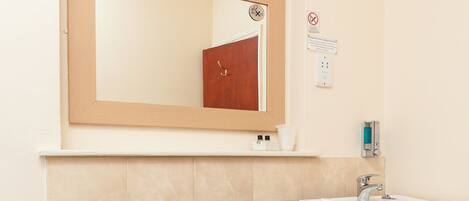 A bathroom with a white sink, a mirror, a toilet, and a towel rack.