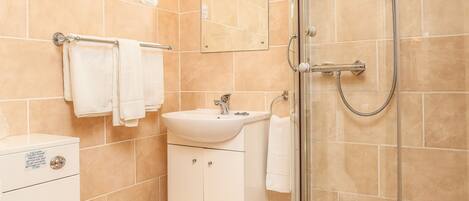 Un bagno moderno con doccia vetrata, un water bianco e un lavandino con specchio soprastante.