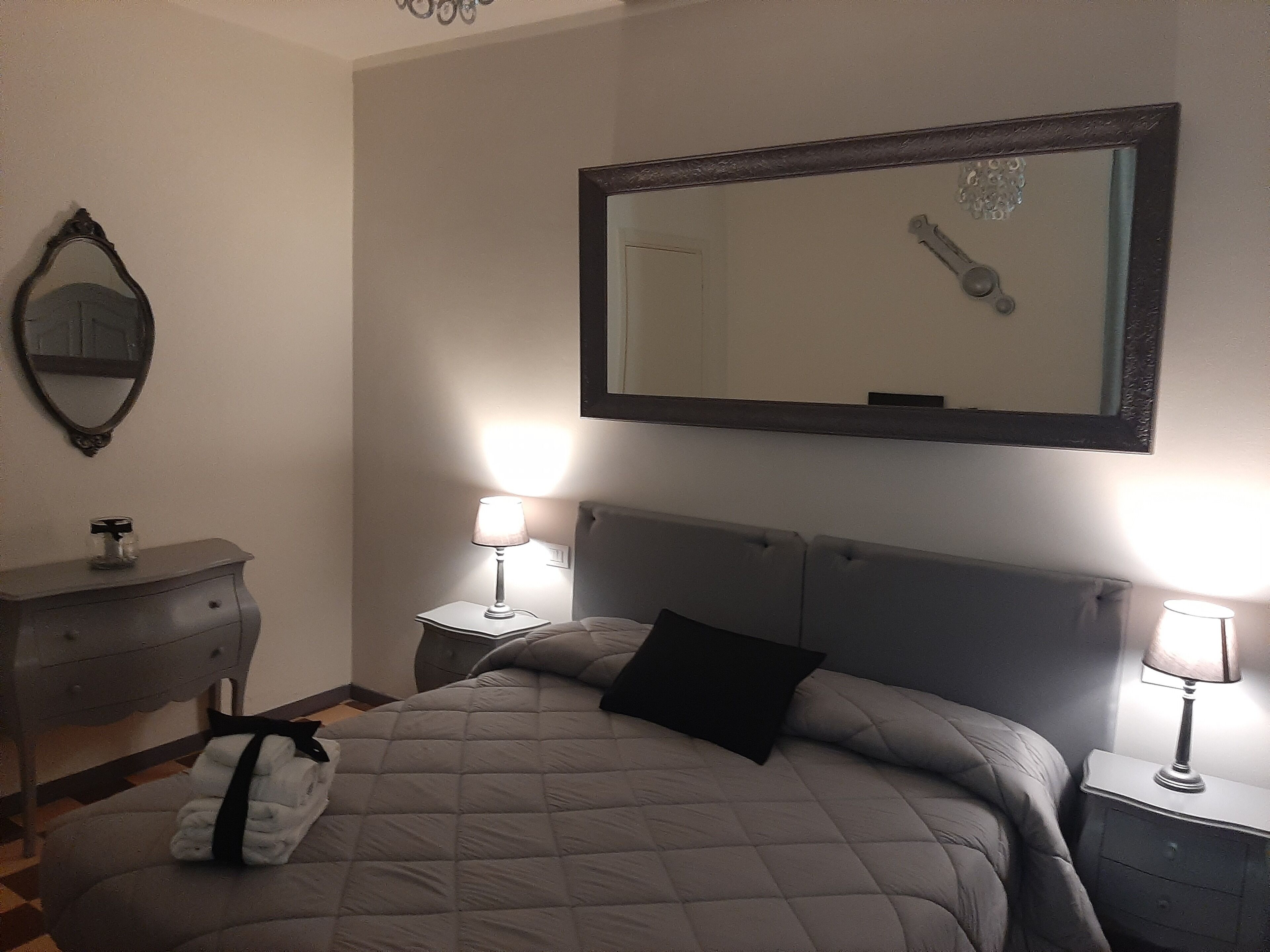 Une chambre à coucher comprenant un lit, deux tables de chevet avec des lampes, une commode, un miroir et une horloge murale.