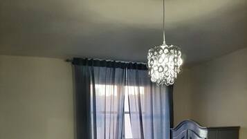 Une chambre à coucher avec un lit, une armoire, un lustre et des rideaux en voile.