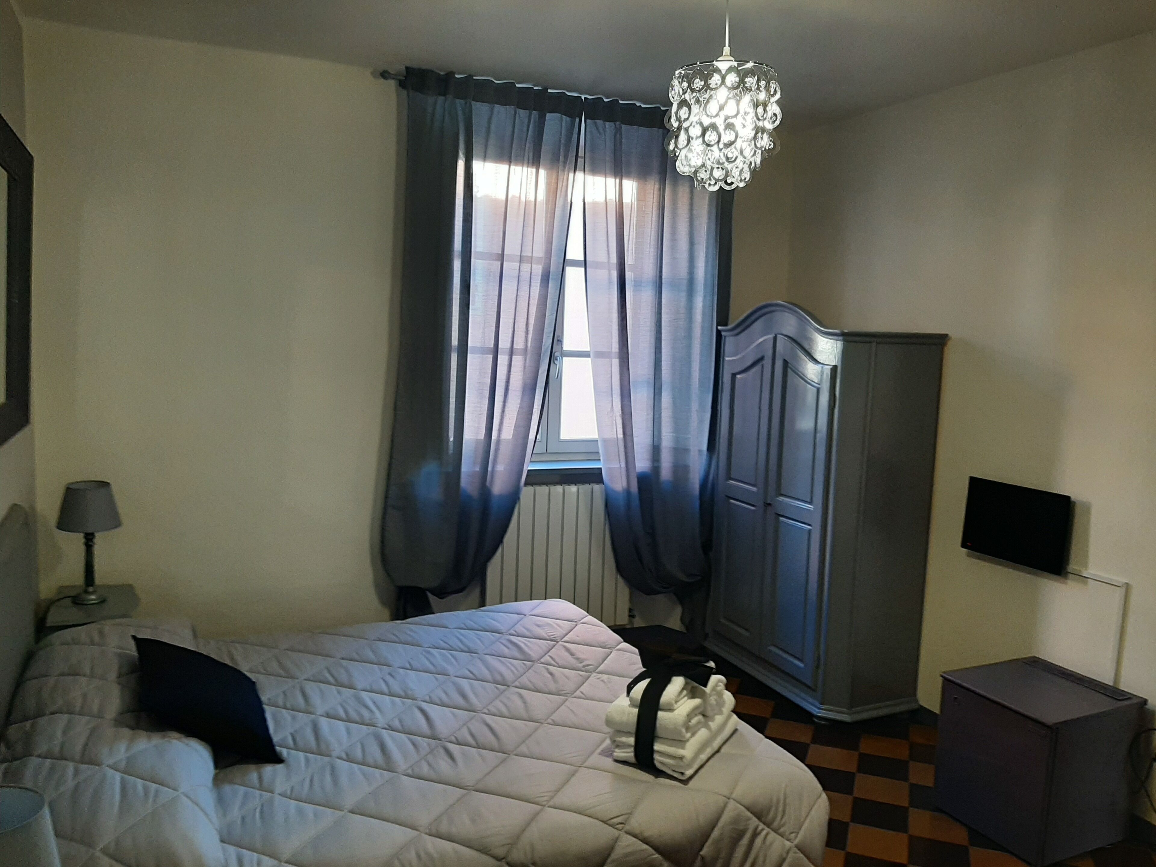 Un dormitorio con cama, armario, televisor y candelabro.