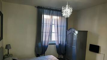 Un dormitorio con cama, armario, televisor y candelabro.
