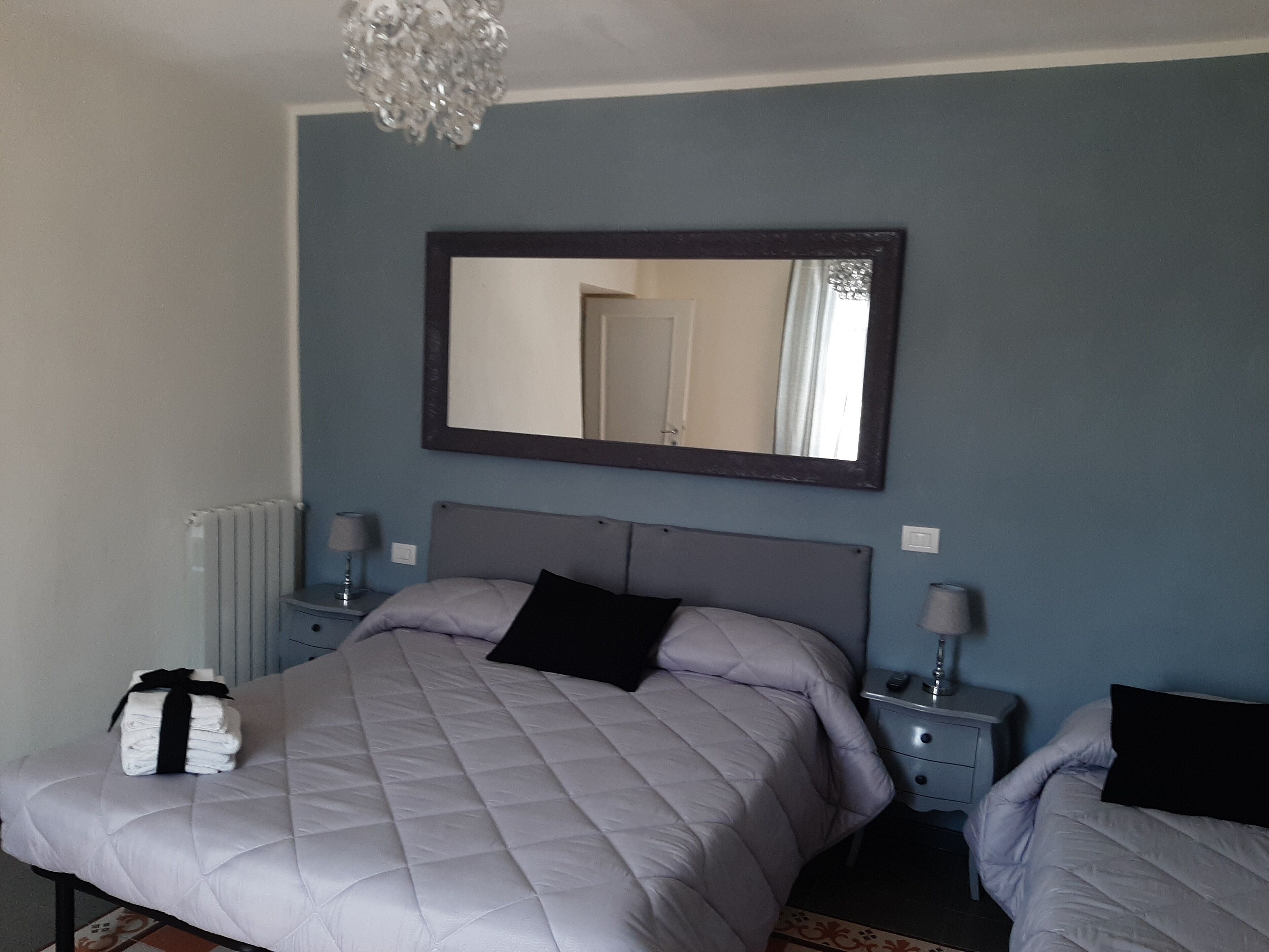 Una camera da letto con un letto, comodini, uno specchio e un termosifone.