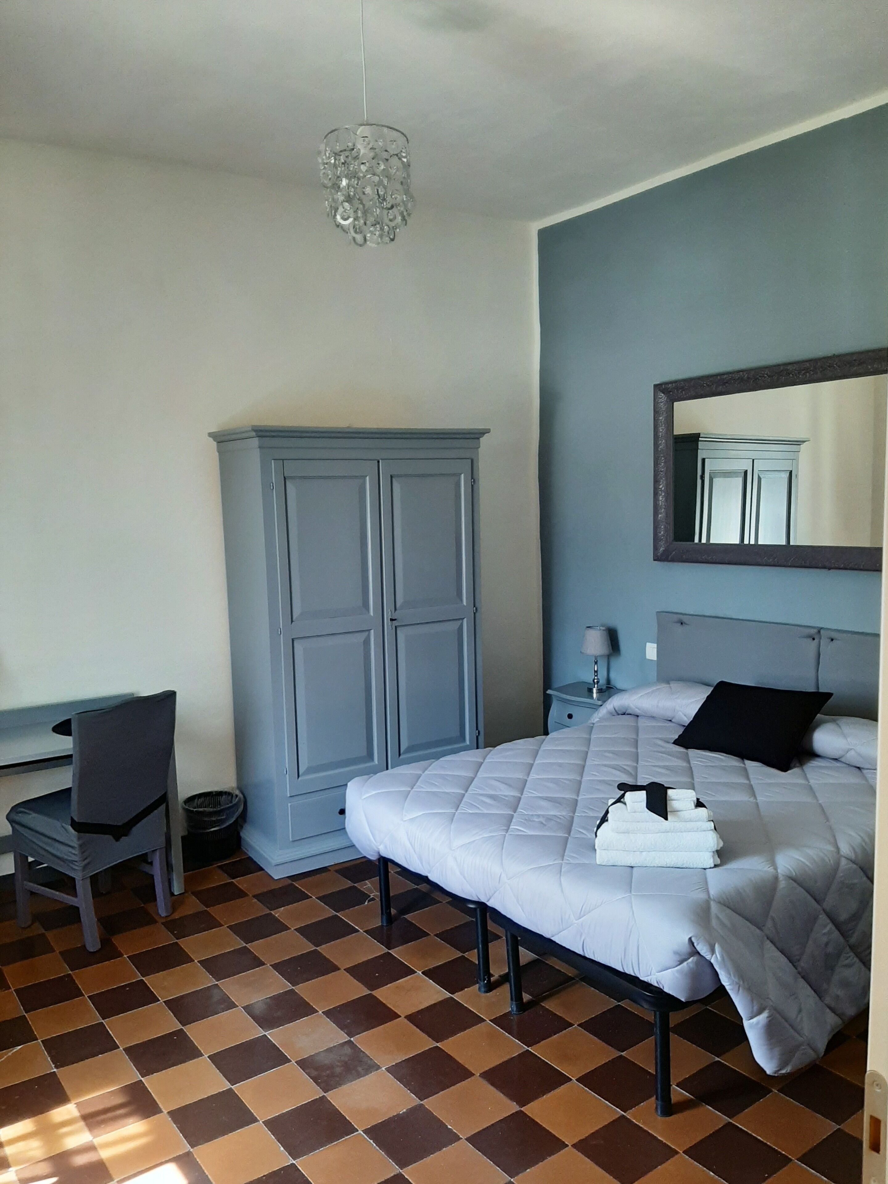 Un dormitorio con cama, armario, escritorio y silla.