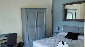 Un dormitorio con cama, armario, escritorio y silla.