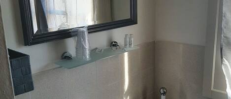 Un baño con lavamanos blanco, un espejo y una cortina de ducha.