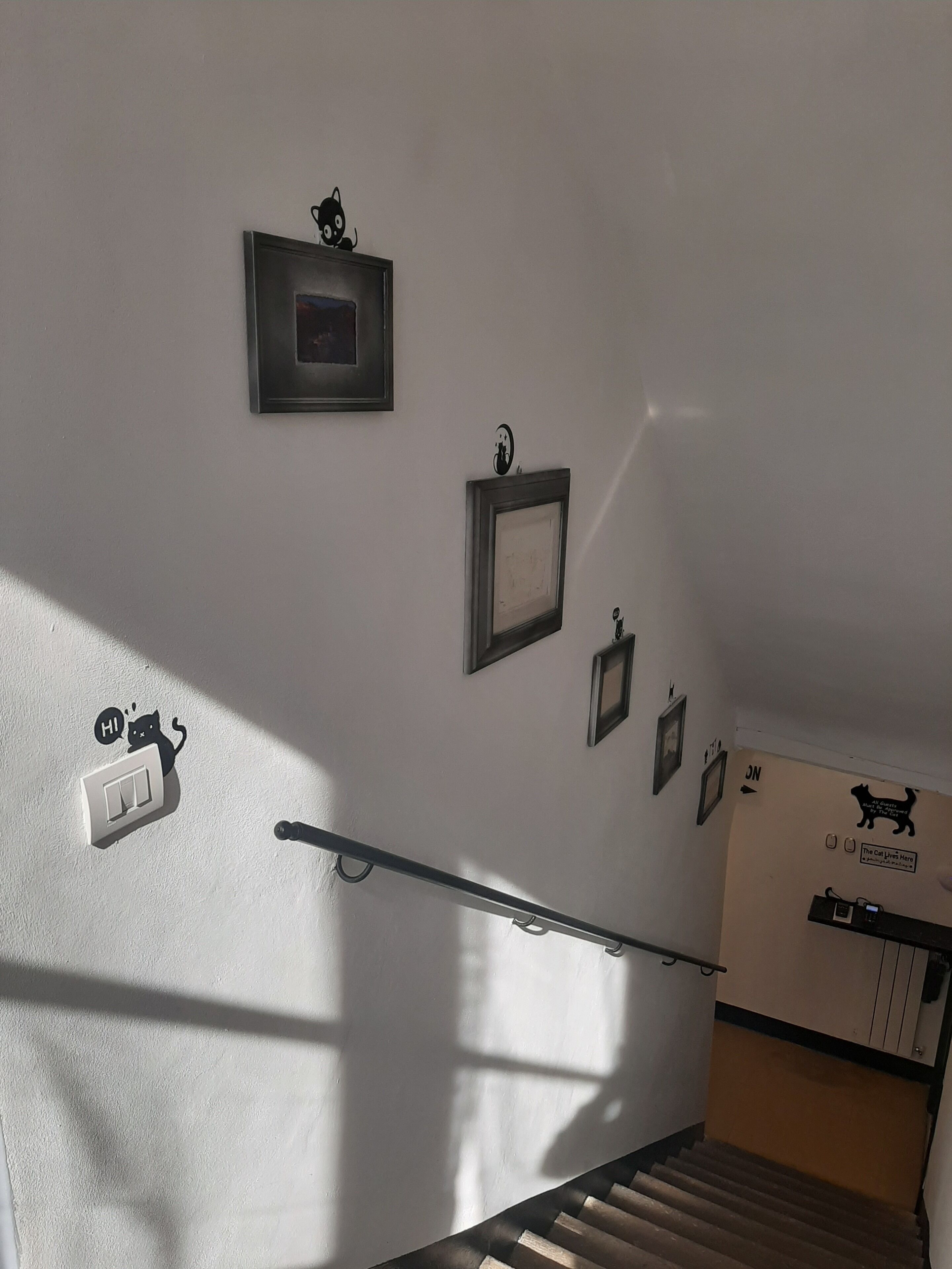 Een trap met leuningen, een lichtschakelaar en foto's aan de muur.