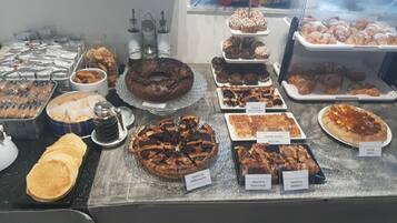 Mostrador de panadería con diversas opciones de repostería, como cruasanes, muffins y tartas.