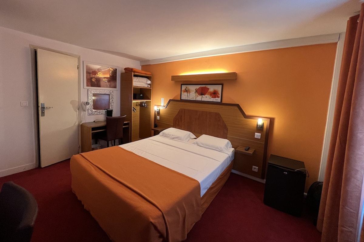 Een hotelkamer met een bed, een bureau, een stoel, een kledingkast en een bijzettafeltje.