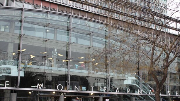 Een modern gebouw met grote glasramen en een zichtbaar bord waarop 