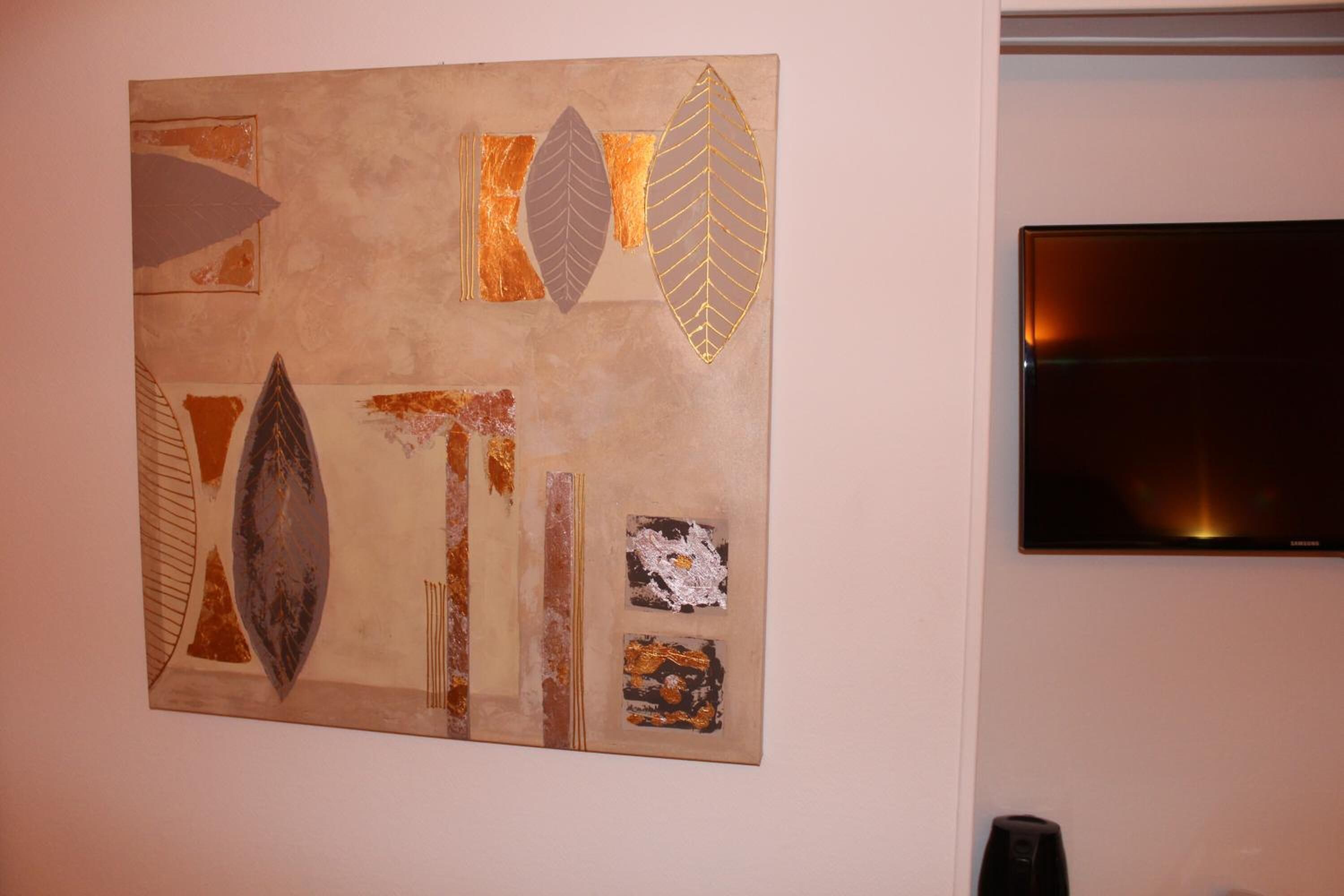 A wall with a large abstract art piece and a flat-screen TV mounted on the wall.