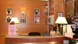Een receptiebalie in een hotel, met ingelijste foto's aan de muur, een bordje 'COMPLET' en een klein model van de Eiffeltoren.