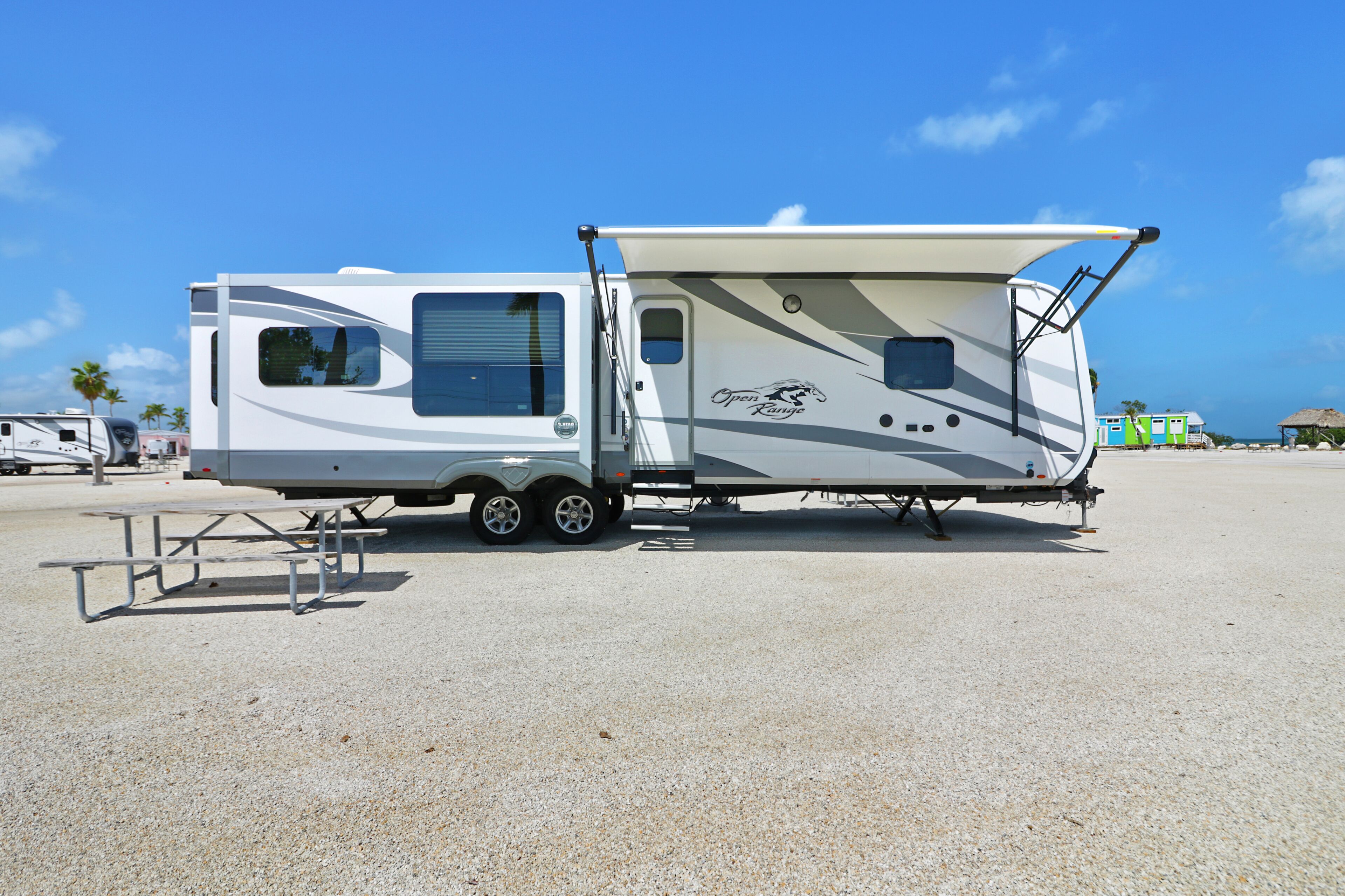A recreational vehicle with a covered living area, a picnic table, and a ramp for wheelchair access.
