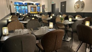 Ein Restaurant mit Tischen und Stühlen, die in Reihen angeordnet sind, mit einer Kerze auf jedem Tisch.
