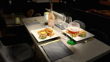 Een eettafel met twee borden eten, een fles wijn en twee glazen.