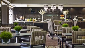 Un restaurante moderno con decoración en tonos oscuros, varias mesas y sillas.