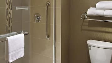 Ein Badezimmer mit einer gläsernen Duschkabine, einer weißen Toilette und einem Handtuchhalter mit Handtüchern.