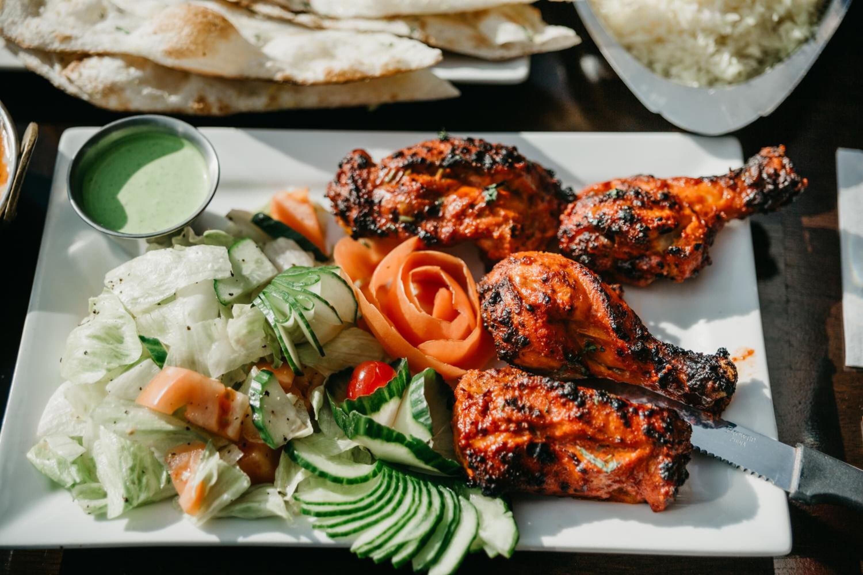 A plate of grilled chicken, salad, and flatbread.