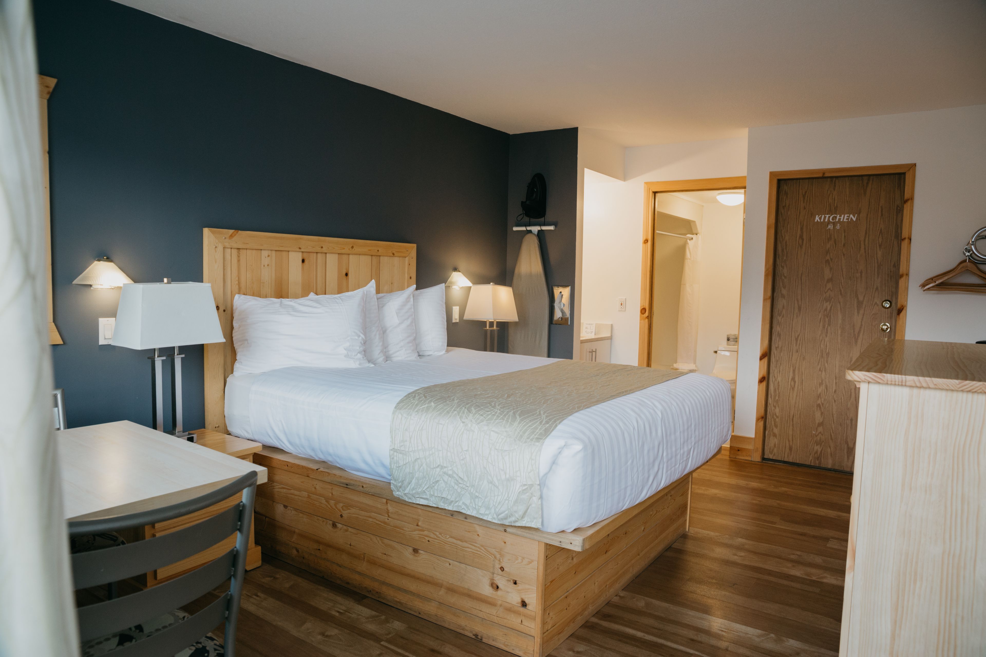 A neatly arranged bedroom with a wooden bed, bedside tables with lamps, a small table, and a wardrobe.