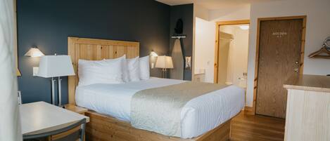 Quarto bem arrumado com cama de madeira, mesas de cabeceira com luminárias, uma mesinha e um guarda-roupa.