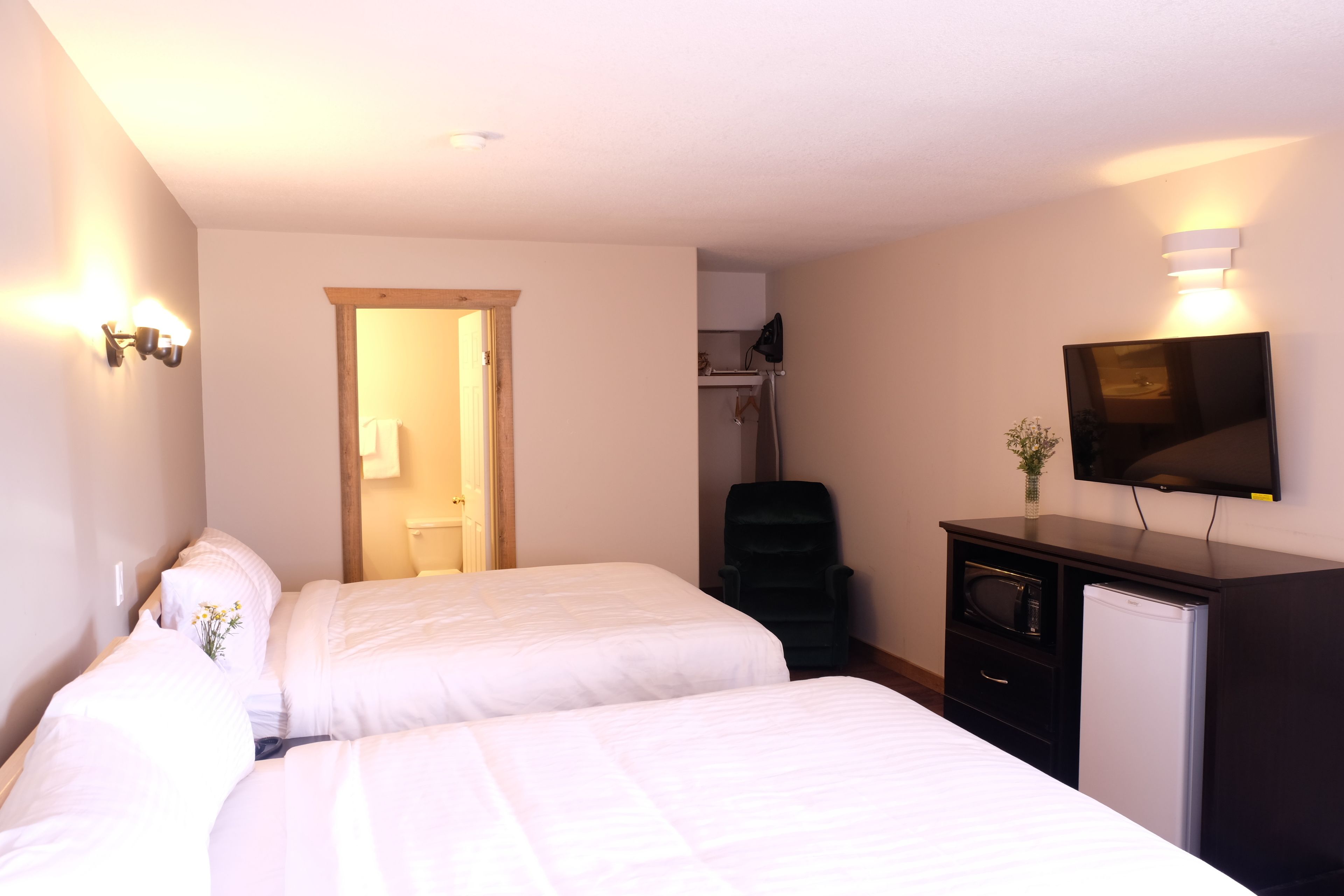 A hotel room with two beds, a TV, a desk, and a chair.