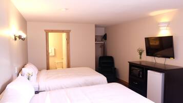 A hotel room with two beds, a TV, a desk, and a chair.