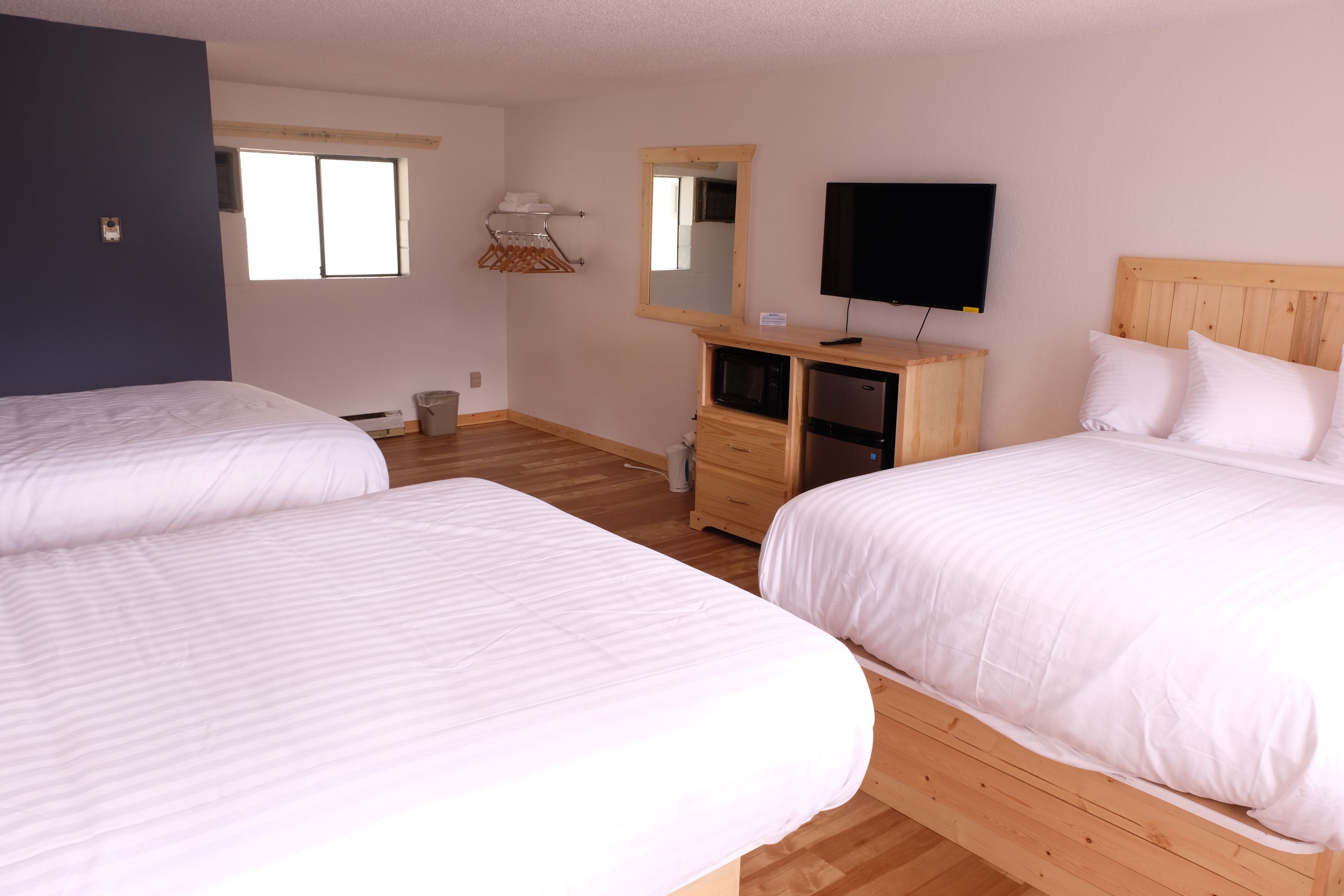Habitación de hotel con dos camas, un aparador de madera, un televisor y una ventana.