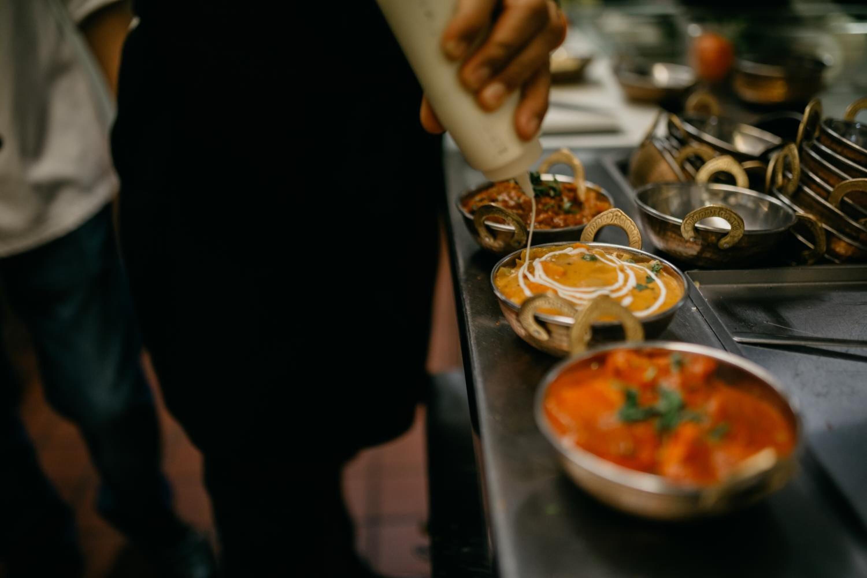 Una persona sirviendo salsa en un bol de comida.