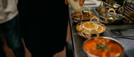 A person pouring sauce into a bowl of food.
