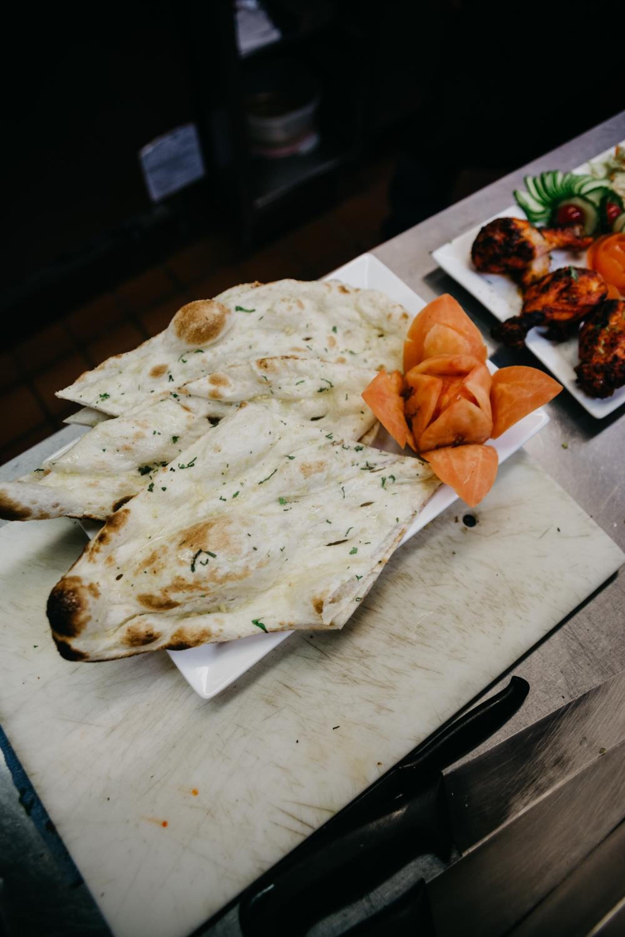 Une table avec du pain plat, un légume sculpté et de la viande grillée.
